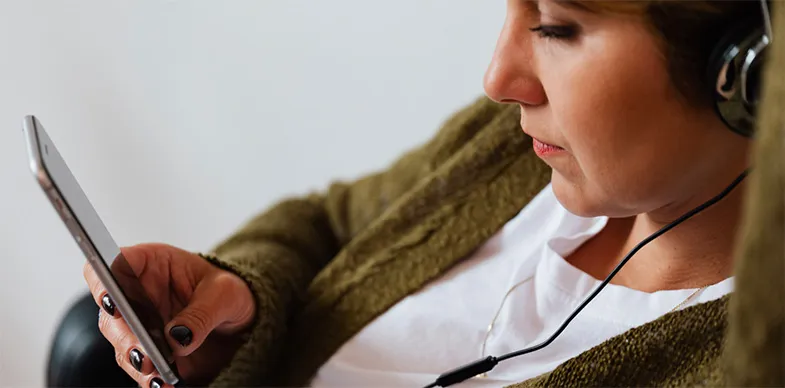 A woman watches a video on her phone while listening through headphones